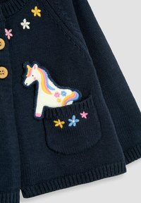 Tamno plava pletena cardigan jakna s drvenim gumbima, koja ima aplikaciju jednoroga na džepu i šarene detalje cvjetnog vezivanja.