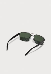 Ochelari de soare cu ramă pătrată, lentile de culoare verde închis, rame metalice negre și brațe din plastic. Dispune de suporturi pentru nas ajustabile pentru confort.