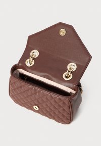 Borsa a tracolla marrone trapuntata con hardware dorato. Presenta una chiusura a scatto e una fodera interna morbida. Forma compatta e rettangolare con una tasca interna.