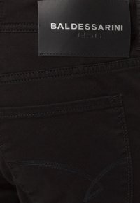 Zwarte spijkerbroek met een leren label waarop "BALDESSARINI JEANS" staat. Voorzien van zichtbare stiksels en zakdetails met een matte afwerking.