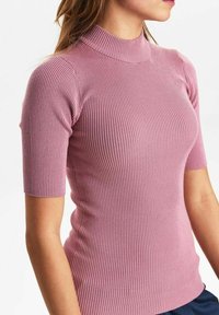 Kortärmad ribbad polokrage i mjuk rosa tyg, med en tight passform och texturerad yta, som framhäver en modern silhuett.