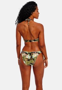 Bloemenbikini set met een haltertop en hoge uitsnede onderkant. Zwarte stof met groene bladeren en witte bloemen; gestructureerde, gladde afwerking.