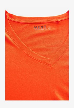 Tricou din bumbac portocalie cu guler în V, având o textură netedă și cusături curate de-a lungul gulerului și marginii. Eticheta logo este vizibilă.