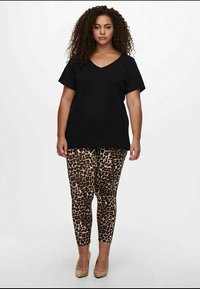 Crna v-neck majica s kratkim rukavima, uparen s smeškastim tajicama s smeškastim uzorkom. Bež štikle upotpunjuju odjevnu kombinaciju. Jednostavan dizajn i kroj.