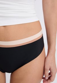 Fondo de bikini negro con una textura suave, que presenta tres rayas horizontales en colores claros en la cinturilla. Forma y diseño clásicos.