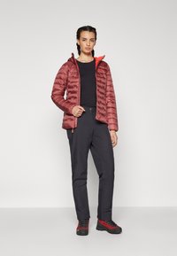 Padded red jacket with a hood and orange accents, paired with black pants and red hiking shoes. Smooth texture with quilted design.