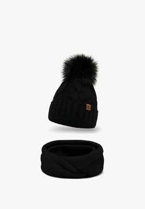 Sort strikket hue med kabeldesign og fluffy pompon, parret med et matchende sort strikket infinity-halstørklæde. Blød tekstur, komfortabel pasform.