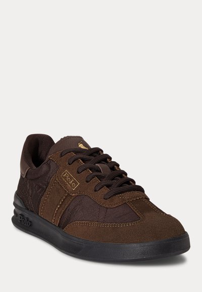 Brun Polo-sneaker med paneler i semsket skinn og lær, svart såle, merket med gullfarget "Polo" og logo nær skolissene, med svarte lisser.