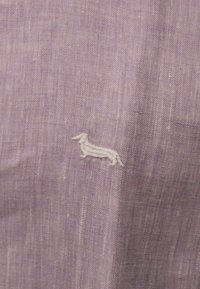 Tessuto viola testurizzato con un sottile ricamo bianco a outline di un bassotto, che mette in mostra un design semplice e materiale morbido.