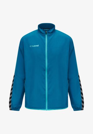 Hummel-Jacke in lebhaftem Blau mit hohem Kragen und durchgehendem Reißverschluss. Verfügt über ein schwarz-graues Zickzackmuster an den Ärmeln, elastische Bündchen und Seitentaschen.