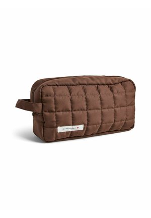 Pochette rectangulaire marron matelassée avec fermeture éclair et poignée latérale, avec une petite étiquette blanche portant du texte et un cœur rouge.