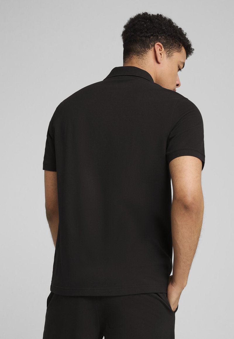 Polo shirt nero a maniche corte con colletto classico e orlo dritto. Texture liscia e design aderente, mostrato da dietro.