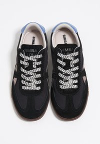 Schwarze Leinensneaker mit Wildlederüberzug, ausgestattet mit gemusterten grau-schwarzen Schnürsenkeln, einem hellblauen gepolsterten Kragen und einer braunen strukturierten Sohle.