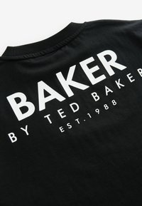 Juodas marškinėlis su ryškiai balta užrašu: "BAKER BY TED BAKER EST. 1988" ant nugaros. Pagaminta iš medvilnės, su apvaliu kaklu.