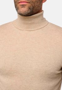Beige Rollkragenpullover aus strukturiertem Strickstoff. Enganliegendes Design mit hohem, geripptem Kragen. Feine Farbvariationen im gesamten Artikel.