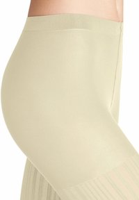 Leggings leggeri color beige chiaro fino al ginocchio; vita a coste; tessuto testurizzato con una finitura liscia; presenta una leggera lucentezza lungo la gamba.