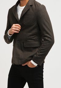 Braune Wollmischjacke mit Kerbkragen, Ein-Knopf-Verschluss und Brusttasche. Verfügt über Seitentaschen und eine strukturierte Oberfläche.