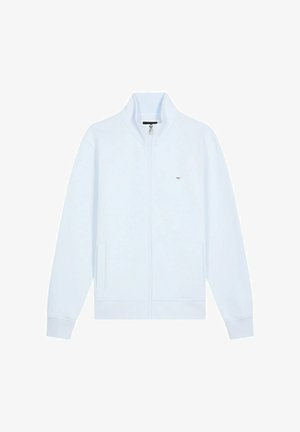 Veste zippée bleu clair en tissu doux. Dispose d'un col haut, de deux poches avant, de poignets côtelés et d'un petit logo sur la poitrine.
