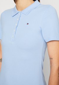 Lichtblauw poloshirt gemaakt van gestructureerde katoen, met een klassieke kraag, korte mouwen en een klein geborduurd logo op de borst.