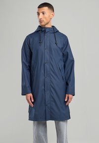 Navy blue waterproof raincoat with a drawstring hood, snap buttons, side pockets, and a straight cut, made from a smooth, synthetic material.