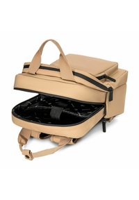 Zaino beige con una texture liscia simile alla pelle, dotato di doppie maniglie, una cerniera superiore e un ampio interno nero con una tracolla imbottita.