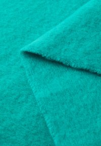 Turquoise felt fabric with soft, textured surface, folded to show thickness and fibrous details. Ideal for crafting and upholstery projects.