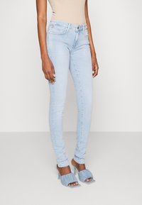 Jeans skinny azul claro con un diseño clásico de cinco bolsillos. Elaborados en denim, presentan una textura suave y un cierre de cremallera con botón.