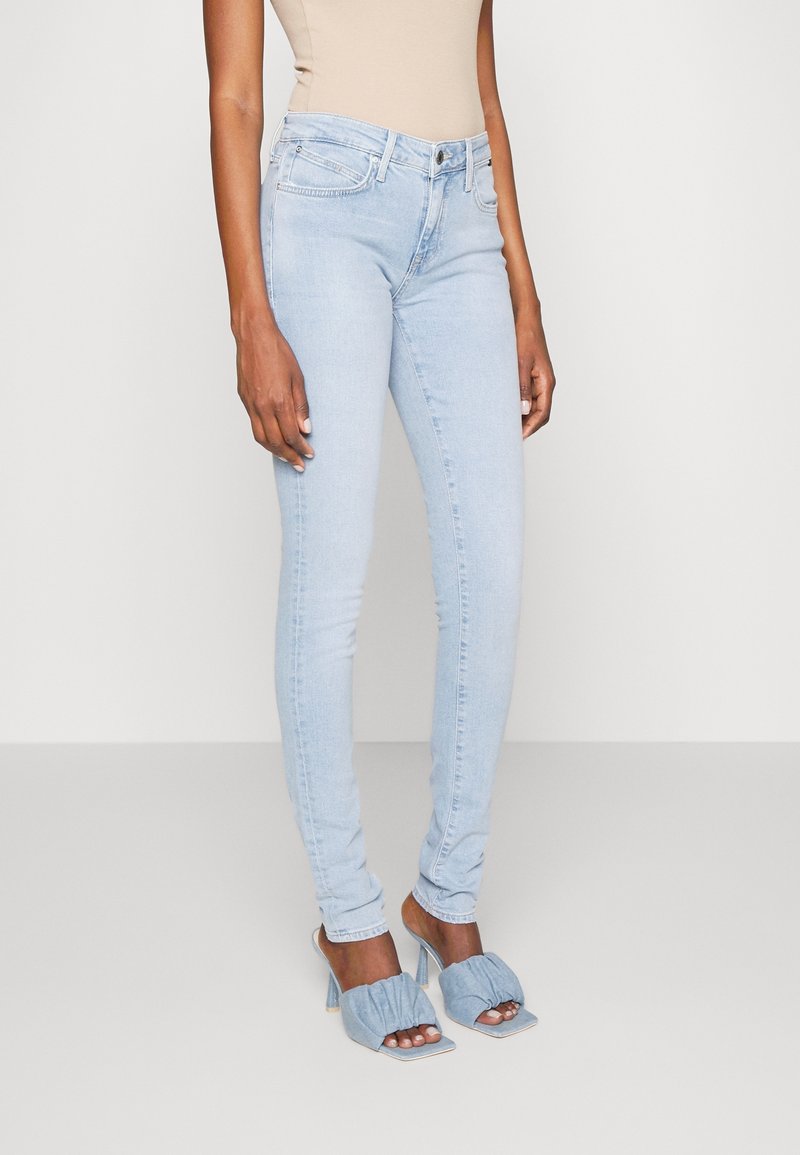 Jeans skinny azul claro con un diseño clásico de cinco bolsillos. Elaborados en denim, presentan una textura suave y un cierre de cremallera con botón.