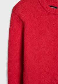 Maglione rosso con scollo rotondo, realizzato in morbido tessuto a maglia testurizzato. Presenta maniche lunghe e un design minimalista senza decorazioni.