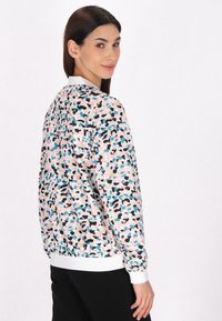 Kravejakke i pink med et multicolort abstrakt mønster. Har hvide manchetter og kant, lavet af et glat stof.