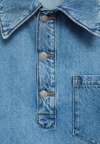 Koszula dżinsowa w jasnoniebieskim kolorze, z zaostrzonym kołnierzykiem, trzema zapięciami na zatrzaski, kieszenią na piersi oraz teksturowanym materiałem z delikatnym blaknięciem.