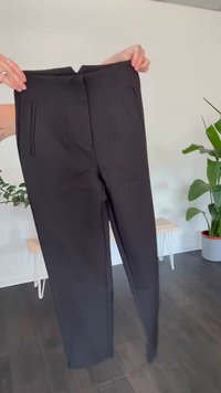 Zwarte broek met plooien aan de voorkant, gemaakt van een gladde stof. Beschikt over een rechte pootontwerp en een middelhoge taille.