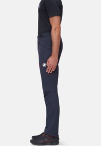 Marine buitenbroek met een slim fit, gemaakt van flexibel materiaal, met ritszakken en een logo op de dij. Gecombineerd met zwarte schoenen.