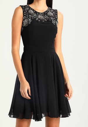 Ärmelloses schwarzes Kleid mit silberner Blumenstickerei auf der oberen Brust und den Schultern, tailliertem Schnitt und einem fließenden knielangen Rock.