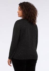 Black long-sleeve top with a round neckline, featuring a speckled pattern in silver tones. Soft texture with a relaxed fit.