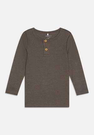 Brown long-sleeve shirt made of ribbed fabric, featuring a rounded neckline, two wooden buttons at the chest, and fitted cuffs.
