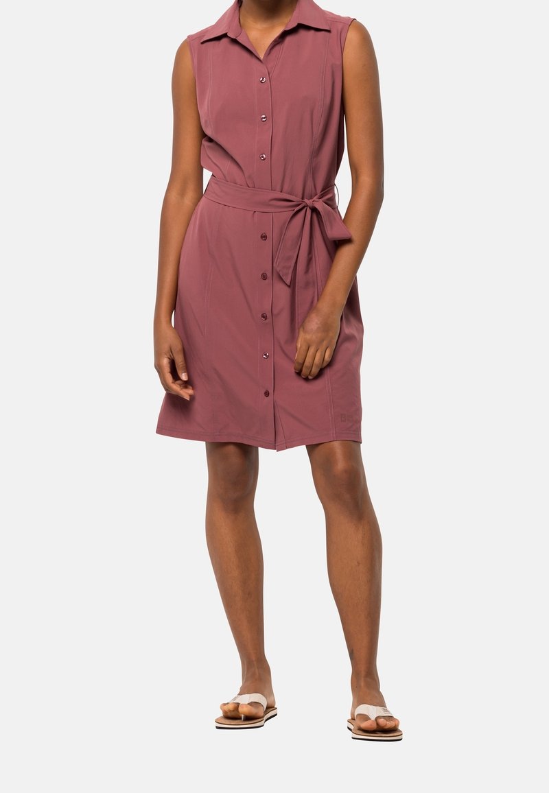 Robe sans manches, longueur au genou, en rose poudré, avec une patte de boutonnage à l'avant, un col et une ceinture à nouer à la taille. Texture de tissu lisse.