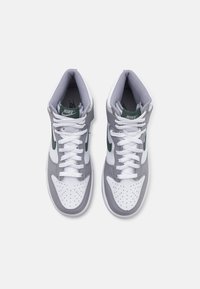 Et par hvite og grå Nike høyhælte sneakers med grønne swoosh-logoer og hvite snøringer sett ovenfra på en hvit bakgrunn.