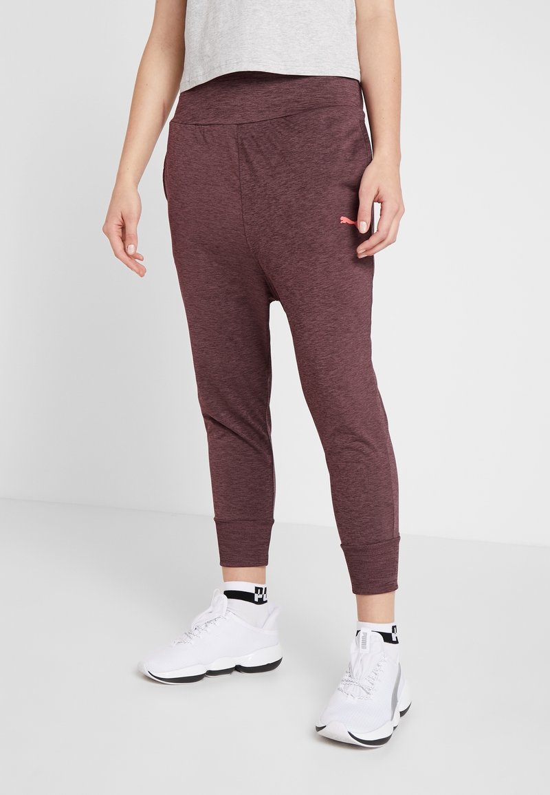 Bordeauxfarbene Jogginghosen mit schmaler Passform, elastischem Bund und Bündchen an den Knöcheln. Besitzt ein kleines pinkes Logo an der Seite. Tragen Sie dazu weiße Sneakers.