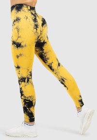 Geel en zwarte tie-dye legging met een zachte, rekbare stof. Hoge tailleband, aansluitend ontwerp en geribbelde textuur aan de bovenkant.