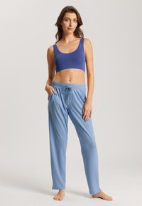 Blauwe bralette met brede bandjes, gecombineerd met lichtblauwe, ontspannen pasvorm broeken met een elastische taille en trekkoord, gepresenteerd op een model.