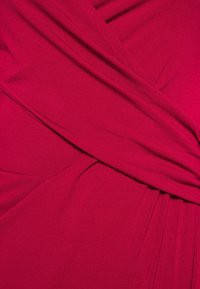 Fuksia pehmeästi laskeutuva kangas, jossa on päällekkäisiä paneeleita ja hienovaraisia poimuja, luoden virtaavan visuaalisen suunnittelun.