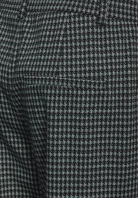 Tessuto nero con un motivo geometrico in azzurro chiaro e bianco, dalla texture liscia e dal design strutturato.