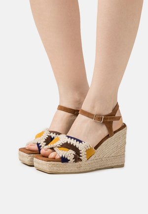 Sandalias cuña marrones con detalles de tela colorida y tacón de yute trenzado. Presentan una correa con cierre de hebilla y un diseño texturizado y tejido.