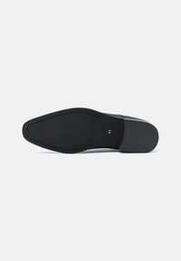 Suela de zapato de cuero negro, textura lisa, forma ovalada, presenta un agarre con patrón, incluye la marca de talla "41" en el borde exterior.