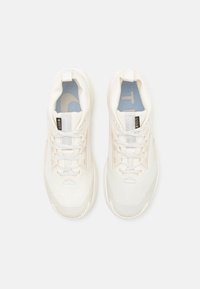 Zapatillas deportivas blancas con parte superior de malla texturizada, puntera reforzada y suela acolchada. Presentan cordones y una plantilla con un patrón azul.