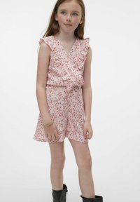 Monos rosa con flores y mangas con volantes, que presenta un diseño cruzado y un acabado texturizado. Llevado con botas negras hasta el tobillo y una pulsera dorada.