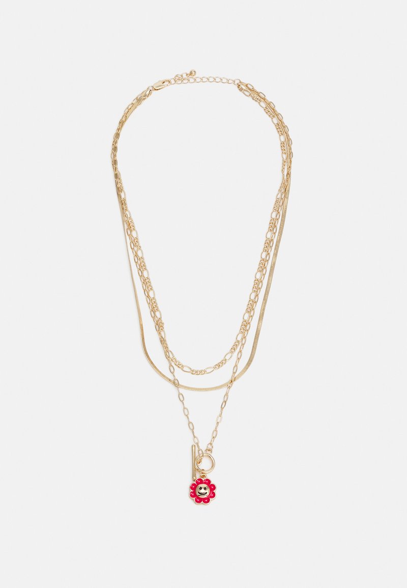 Colar multi-camadas dourado com correntes de espessuras variadas, com um pingente de flor vermelha e um pequeno detalhe de carinha feliz.
