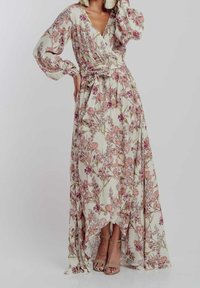 Blommig maxiklänning med långa ärmar, v-ringning och knytmidja. Har en ljus creamfärgad bas med rosa och gröna blommönster.