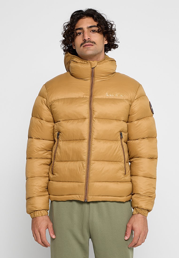 Giacca a vento marrone con colletto alto, motivo a quadrati orizzontali, tasche con zip e polsini elasticizzati. Indossata su pantaloni verdi.